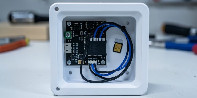 Centrale d’alarme domestique ouverte montrant un module de communication 4G, une carte SIM et des câbles Ethernet dans une ambiance technique réaliste.