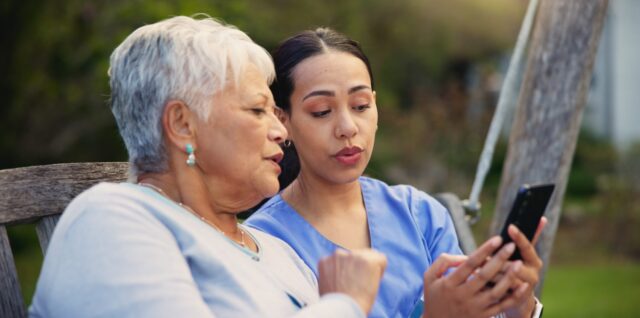 Un aidant consulte l’application MonProxima sur son smartphone à côté d’un majeur protégé.